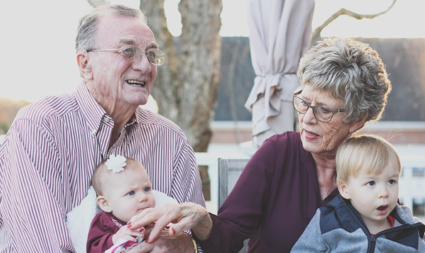 Dos abuelos compartiendo con sus nietos, el articulo destaca el rol emocional del adulto mayor en las familias